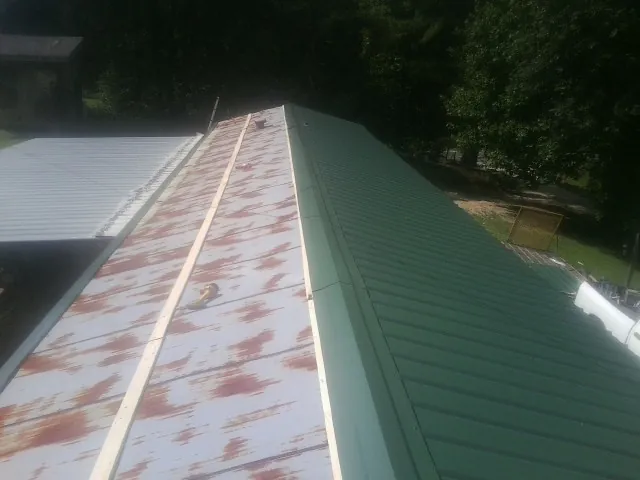 Old rusted panels beside newly installed green metal roofing — Wind Damage Roof Repair by Roofing Brothers in Willard