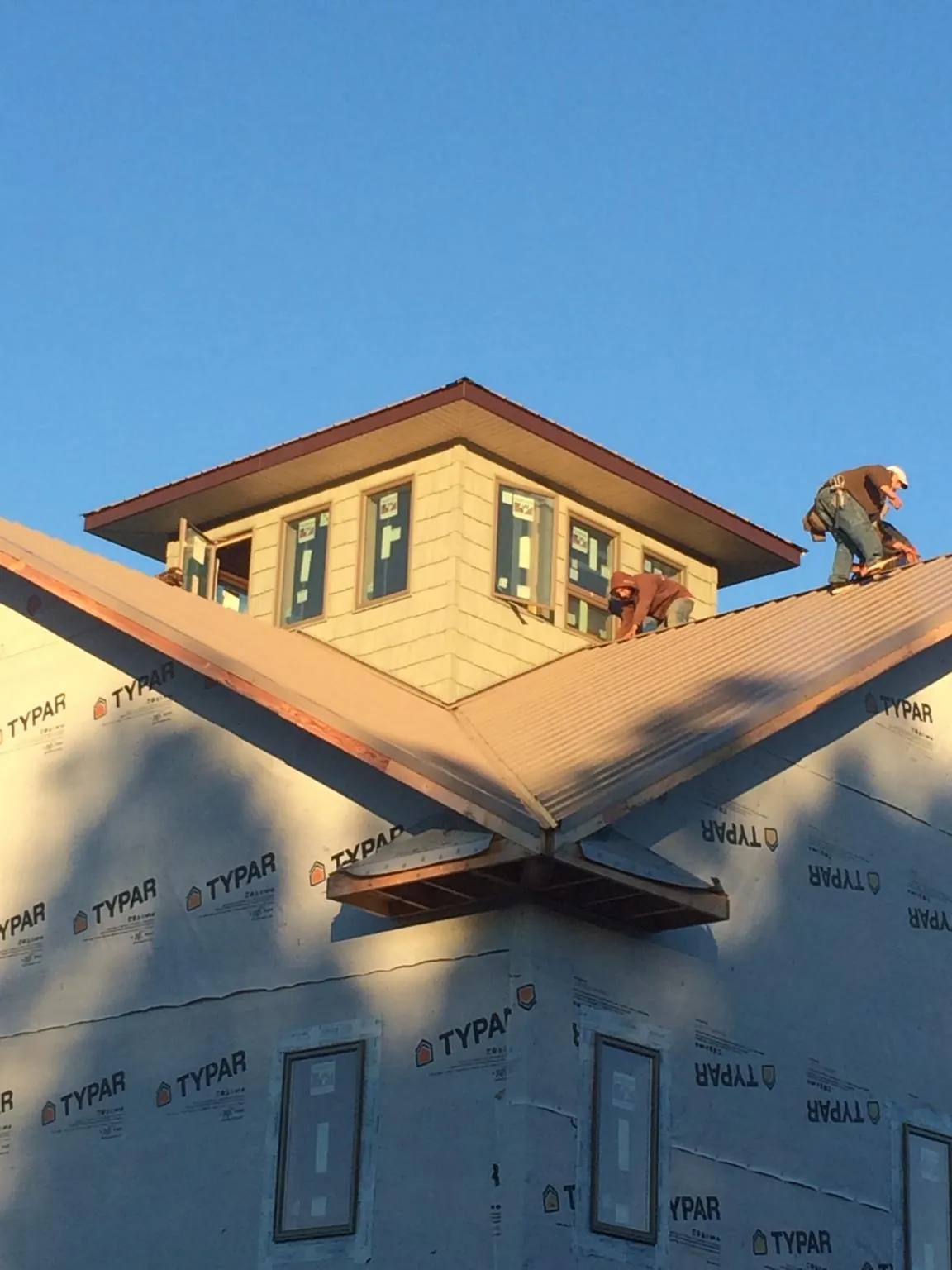 Roofers working around a rooftop cupola on a new metal roof at sunset — Roof Waterproofing in Willard by Roofing Brothers